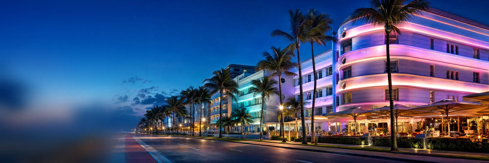 Art Deco hotels at blue hour, their neon glowing.