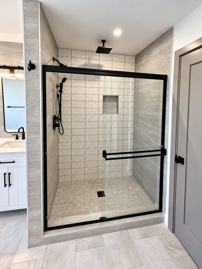 Shower with patterned wall tile, a niche and a black-framed sliding glass door