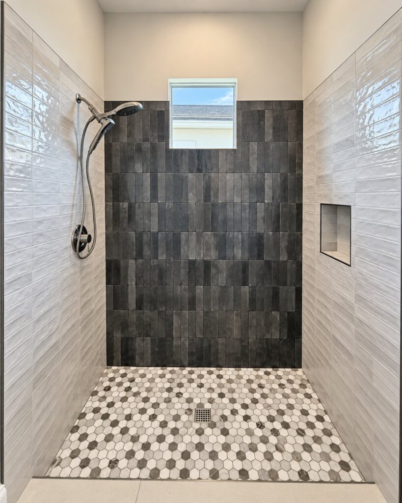 Shower with a charcoal tile feature wall and a hexagon mosaic floor