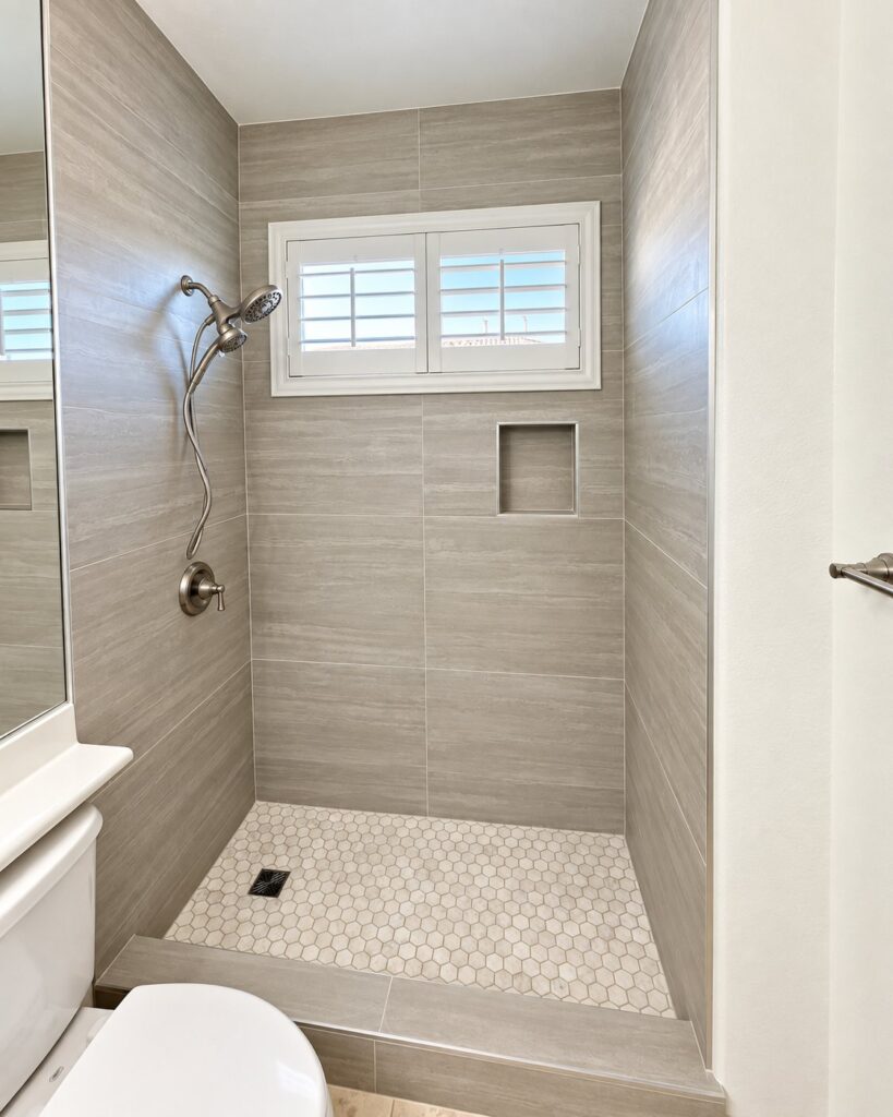 Shower in gray plank tile with a white hexagon floor and a window