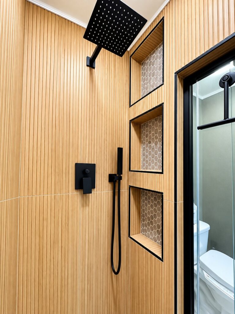 Shower with a wood-look slat wall, three niches and a black rain head