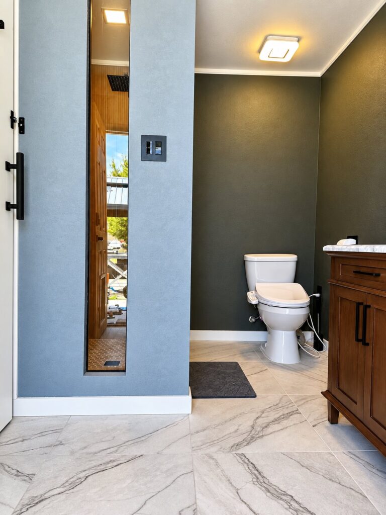 Bathroom with a dark green wall, wood vanity and marble-look floor