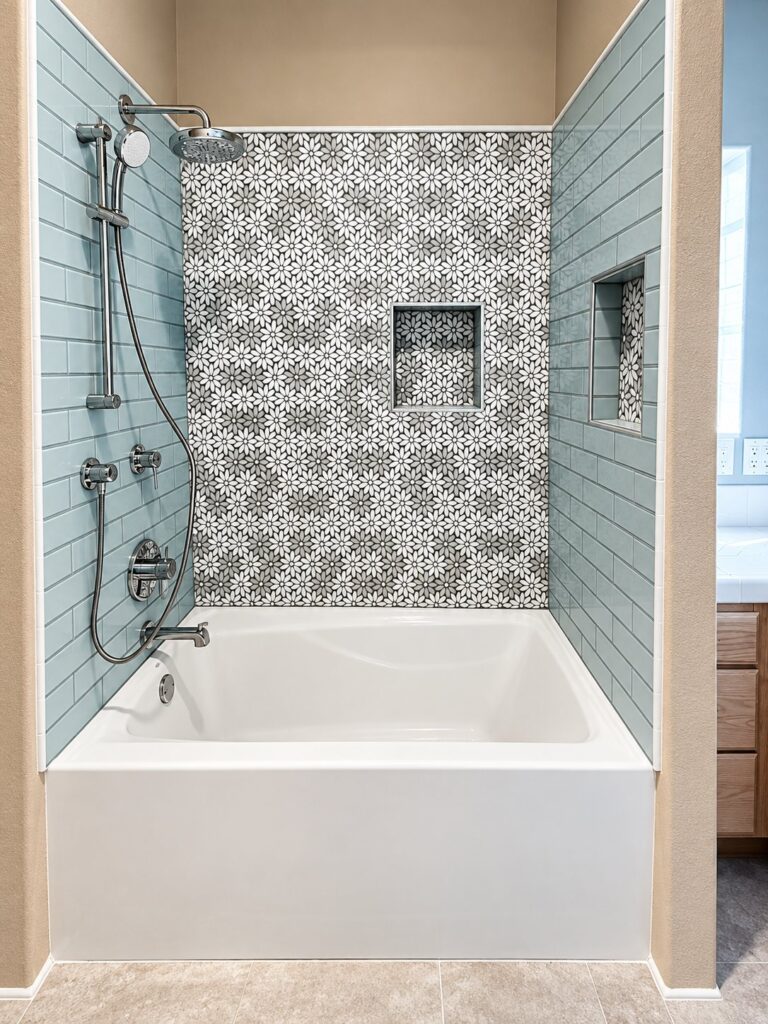 Tub surround in patterned tile with seafoam glass subway tile and a niche