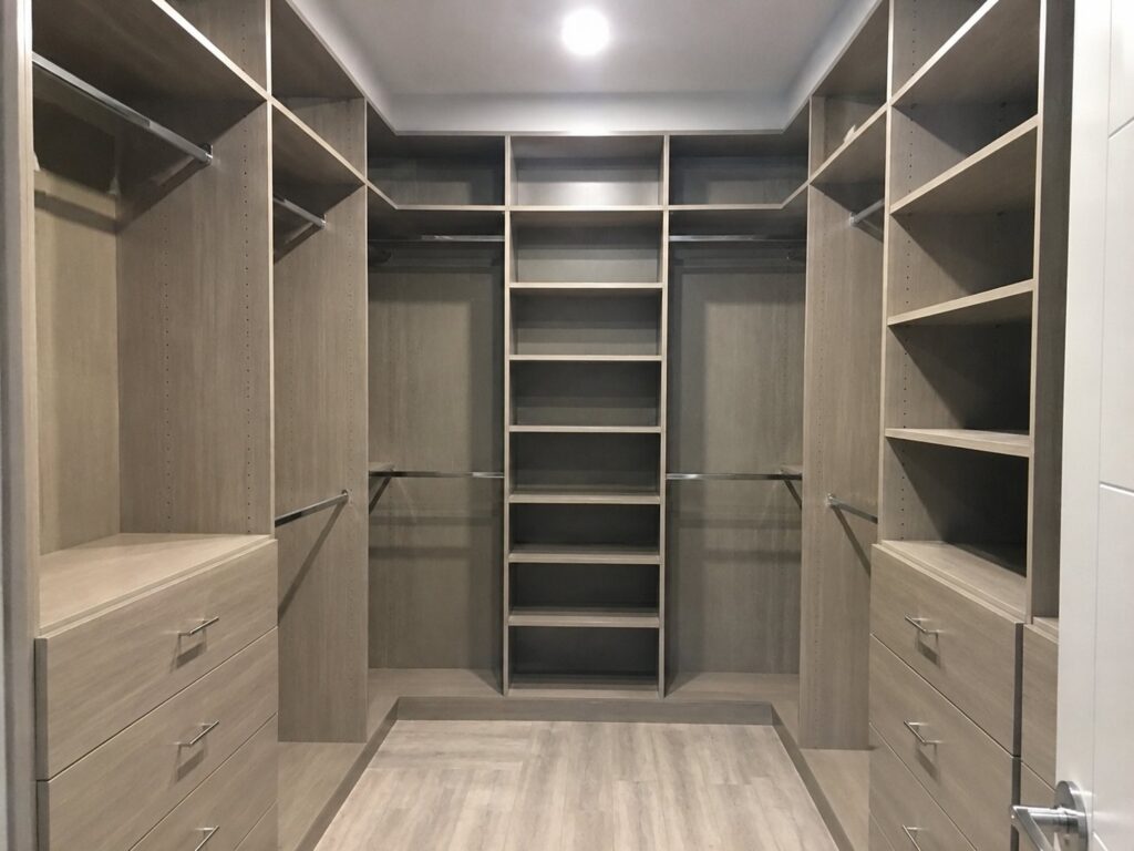 Walk-in closet with gray wood-grain shelving, drawers and hanging rods