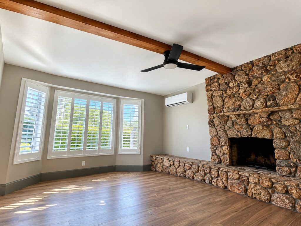 Bedroom with a smooth ceiling, wood beam and stone fireplace