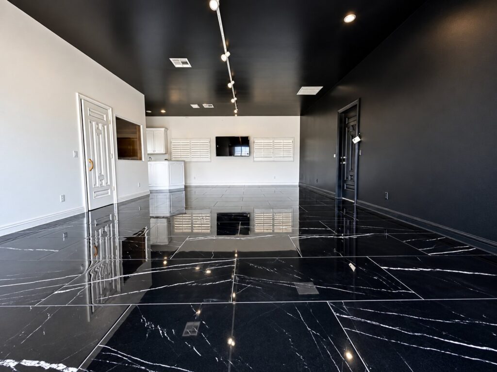 Room with a black ceiling and track lights over a black marble floor