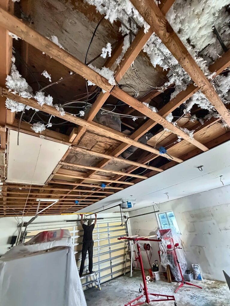 Garage ceiling being hung with drywall on a panel lift