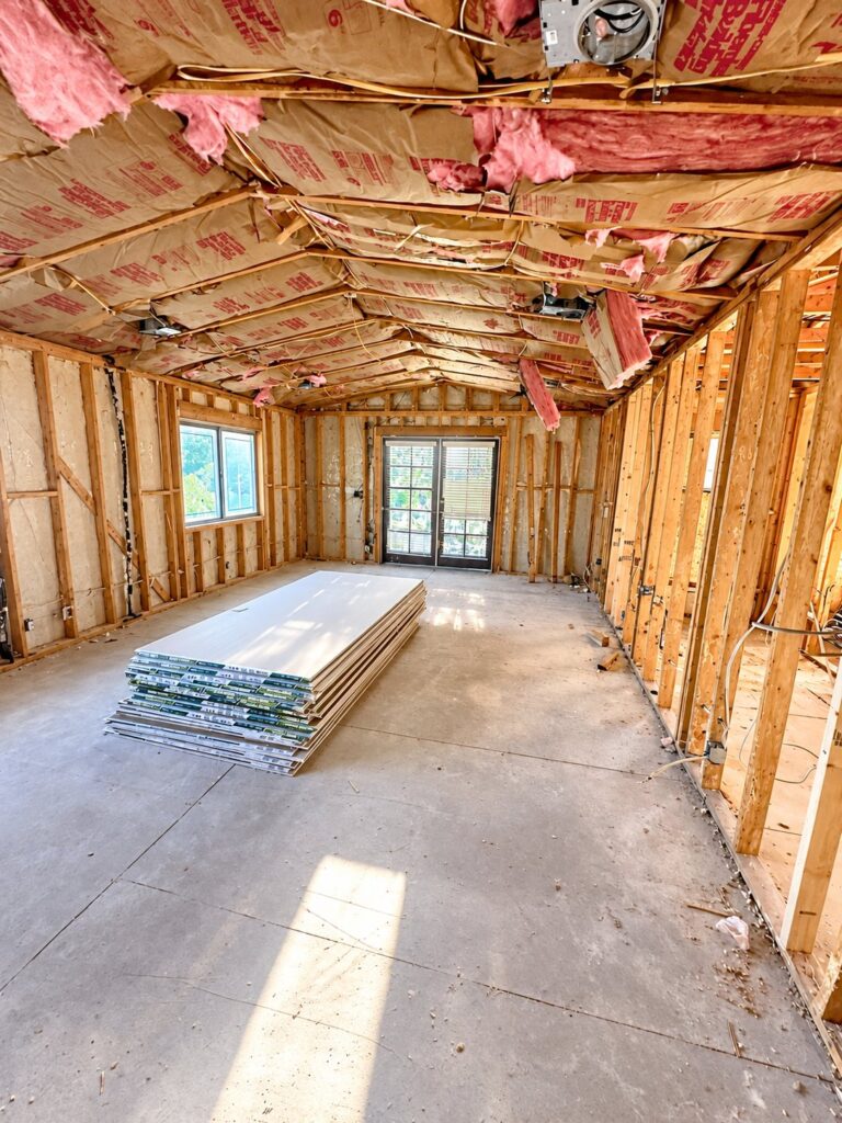 Insulated room with drywall sheets stacked for hanging