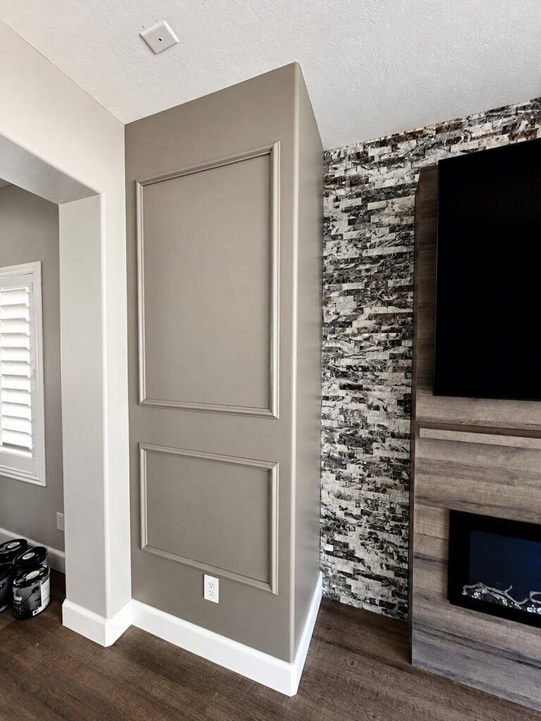 Painted wall panel moldings beside a stone fireplace wall