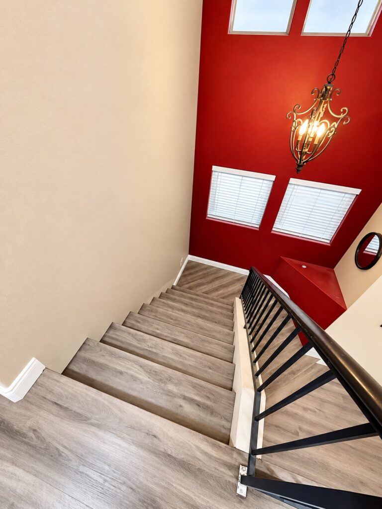 Stairs with new plank treads under a red accent wall and skylights