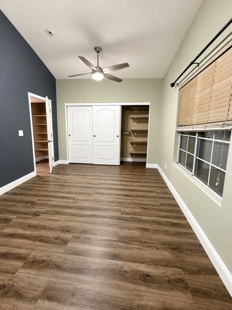 Bedroom with dark wood-look plank flooring and a slate accent wall