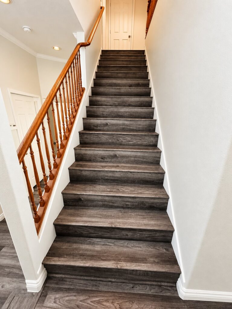 Staircase with dark gray plank treads and an oak handrail