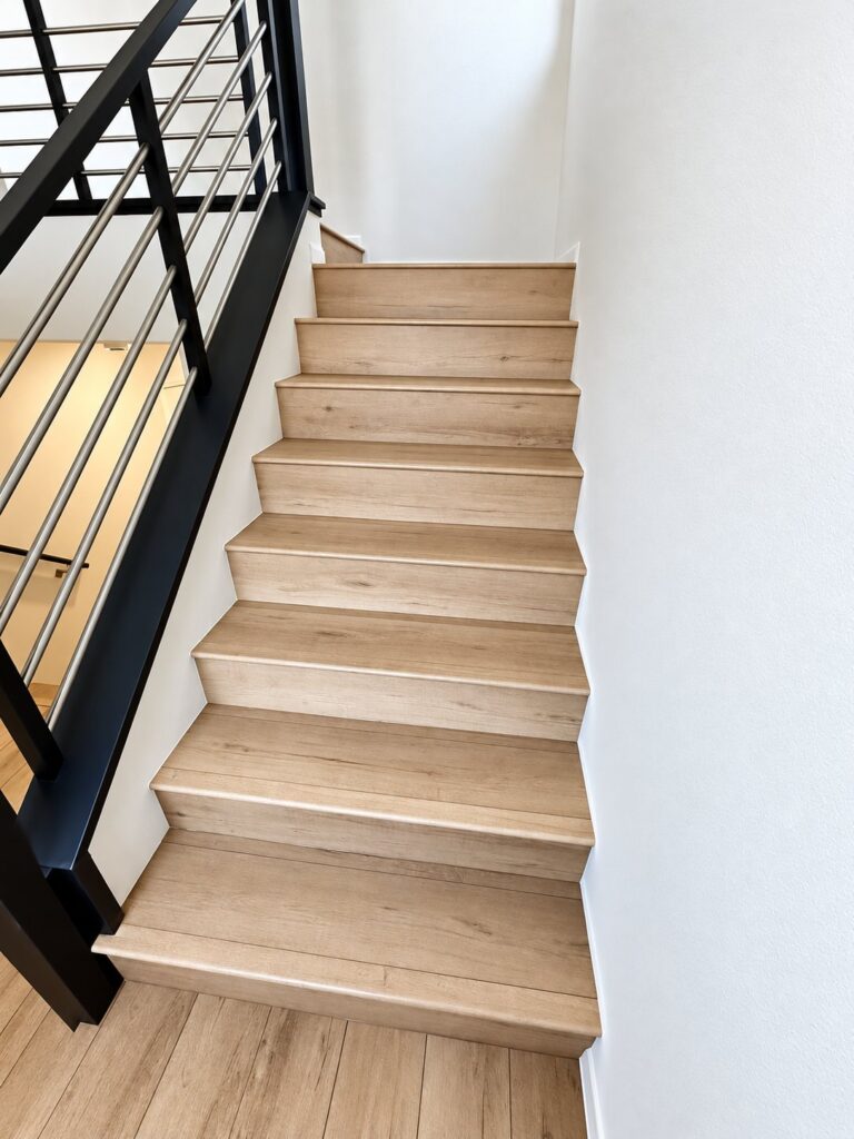 Staircase with light oak treads beside a black metal railing