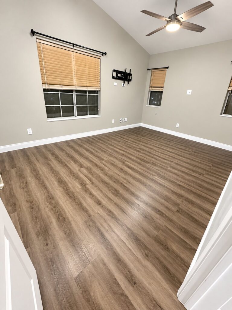 Living room with gray-brown plank flooring under a vaulted ceiling
