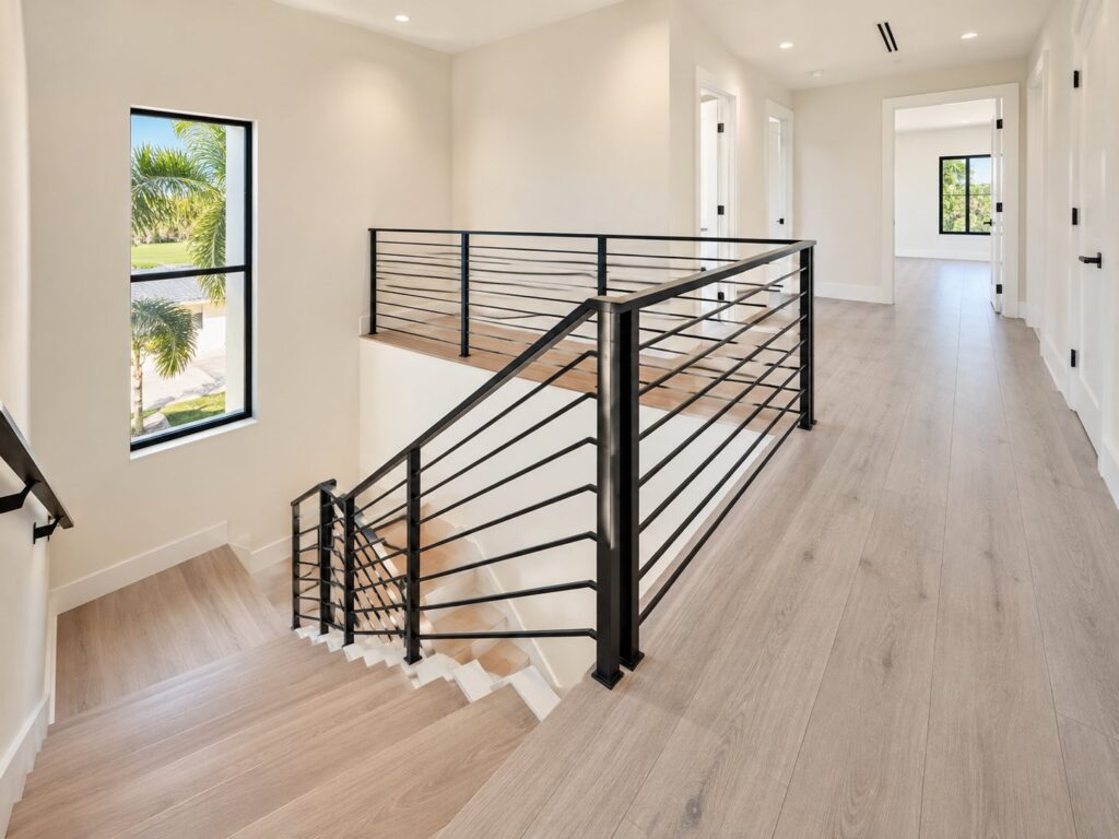 Stair landing with a black horizontal railing and oak floors
