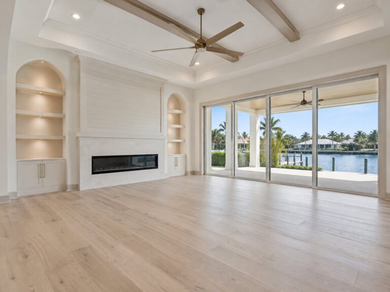 Living room with a beamed ceiling, built-ins and a linear fireplace facing the water