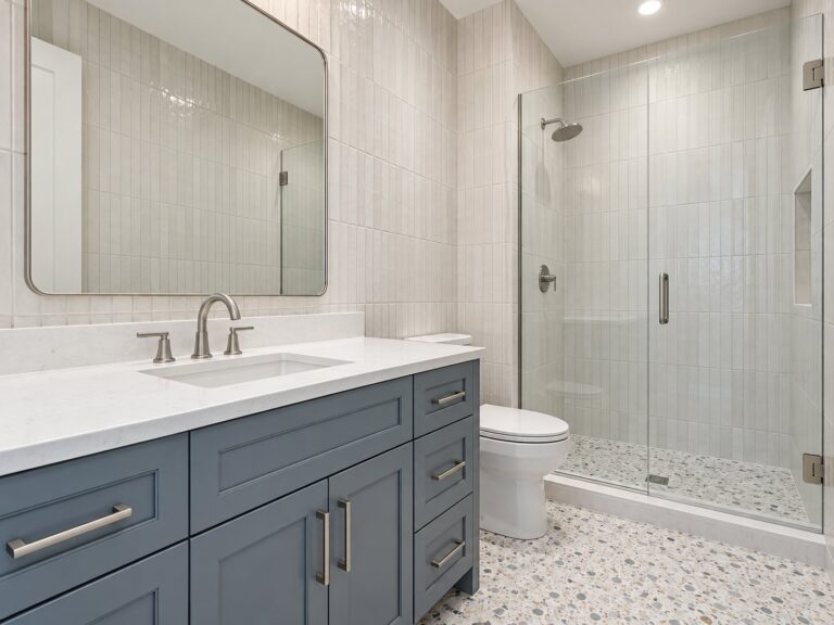 Bathroom with a blue-gray vanity and a glass shower