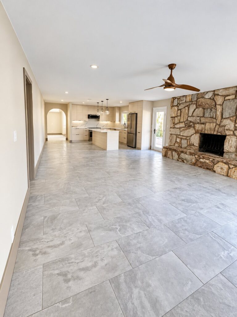 Open-plan living area with a large gray tile floor and a stone fireplace