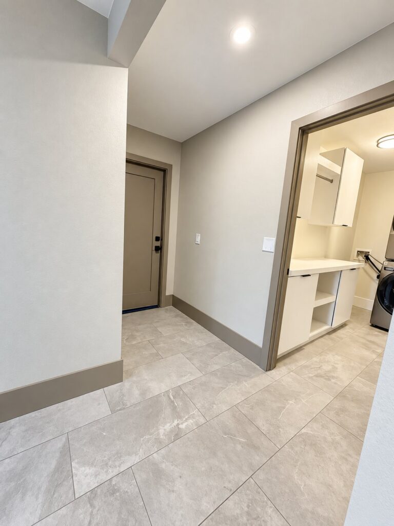 Hallway with gray tile floor, greige doors and the laundry room
