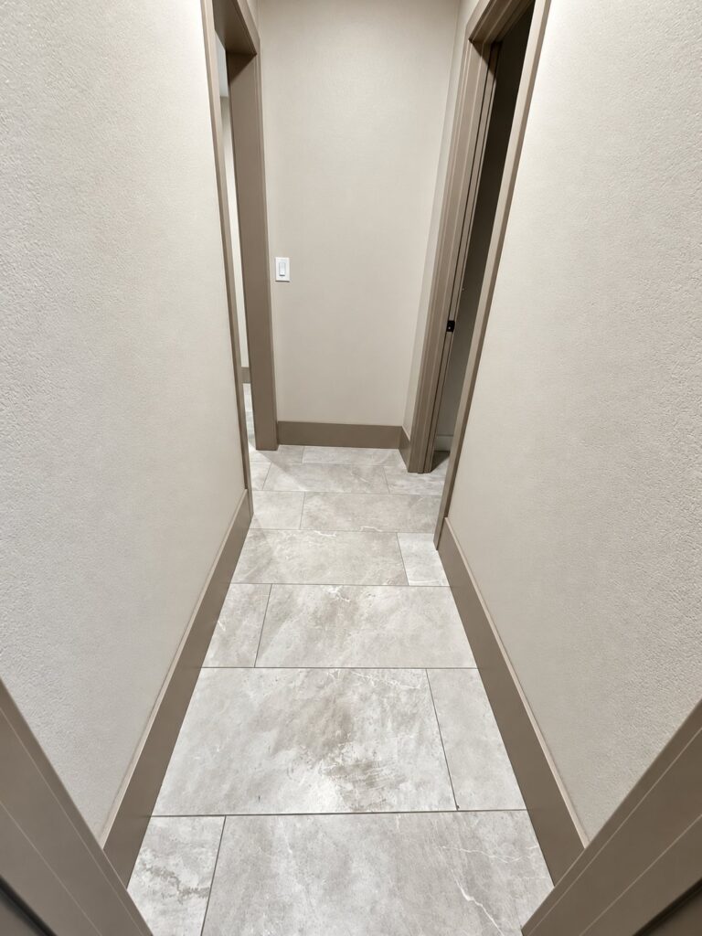 Narrow hallway with gray tile and greige trim