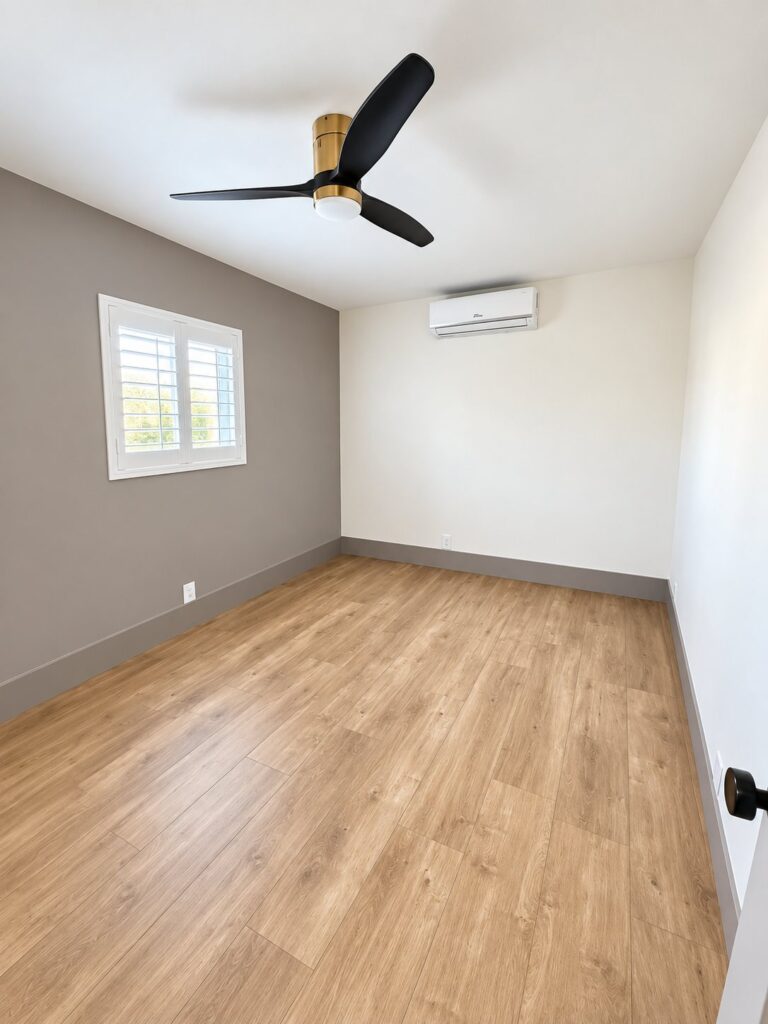 Bedroom with light oak flooring, two-tone walls and a ceiling fan