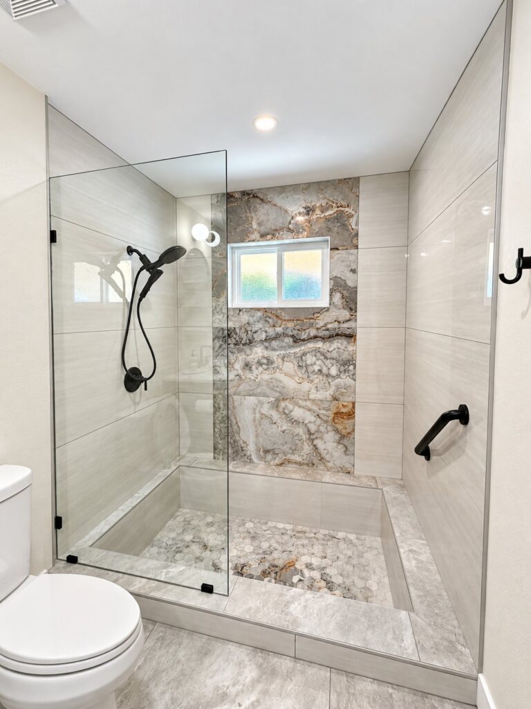 Walk-in shower with a stone feature wall and a frameless glass panel