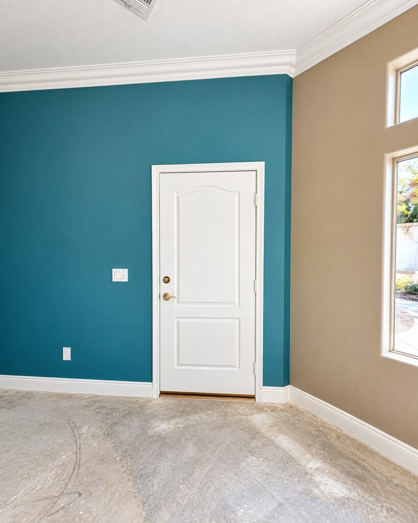 Teal accent wall beside warm beige walls