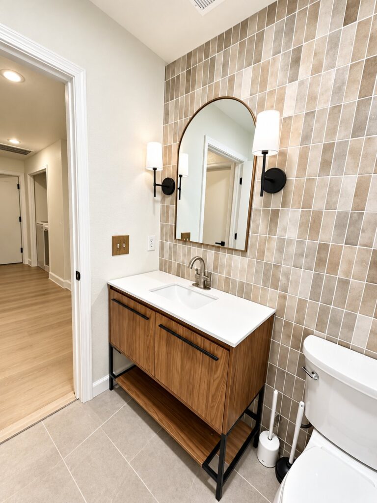 Bathroom with a stacked beige tile wall and a wood vanity