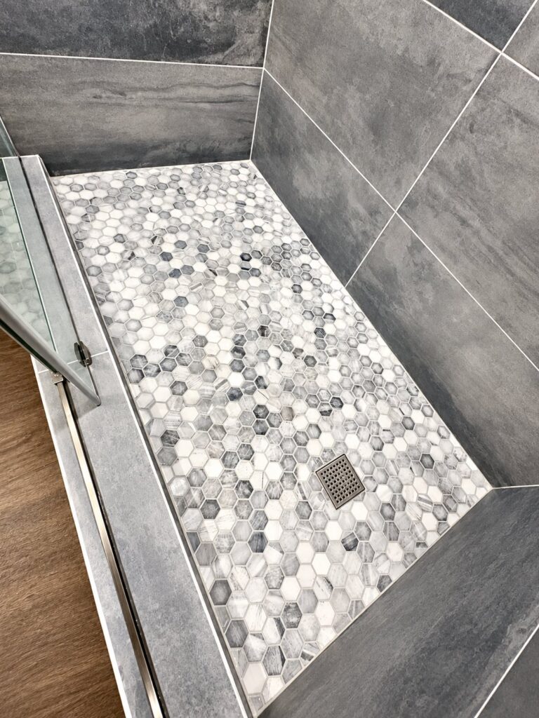 Shower floor in marble hexagon mosaic with gray plank-look walls